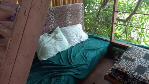 a bed in a tree house with pillows on it at treehouse above the beach in Port Antonio