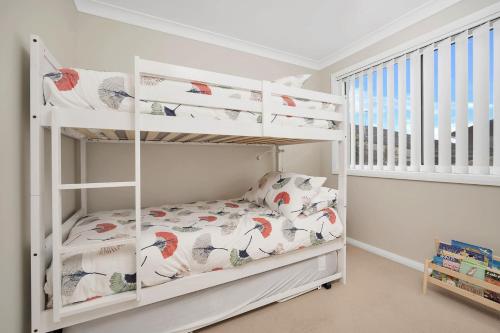 um beliche branco num quarto para crianças com um berço em Banksia by the Sea Gerroa em Gerroa