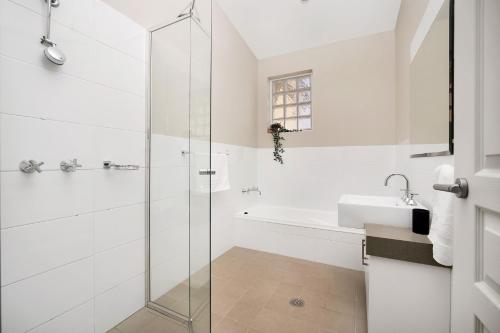 a white bathroom with a shower and a sink at Banksia by the Sea Gerroa in Gerroa