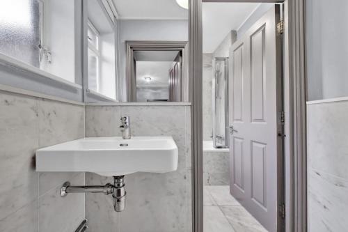 a bathroom with a white sink and a mirror at SERCASA - Cleveland Residence - Fitzrovia in London