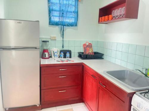 a kitchen with red cabinets and a white refrigerator at Miller's Guest House in Buccoo