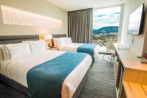 a hotel room with two beds and a large window at Sonesta Hotel Bucaramanga in Bucaramanga
