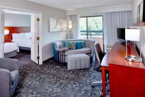 a hotel room with a bedroom with a bed and a desk at Sonesta Select Raleigh Durham Airport Morrisville in Morrisville