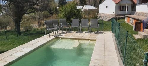 una piscina de agua verde con sillas. en Cabañas del Sol en Potrerillos