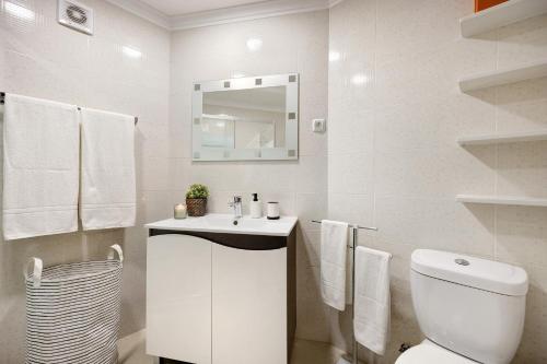 a white bathroom with a toilet and a sink at Casa Farol in Portimão