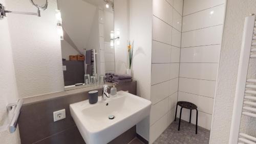 a white bathroom with a sink and a mirror at Neehuus Wohnung 5 in Borkum