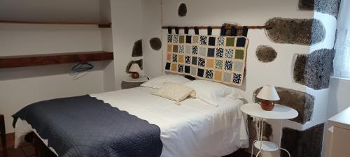 ein Schlafzimmer mit einem Bett und einem Tisch mit einer Lampe in der Unterkunft Casa da Vitória in Santa Cruz da Graciosa