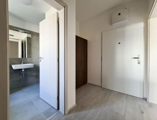 a bathroom with a white door and a sink at Cozy and modern apartment near Brno city center in Husovice
