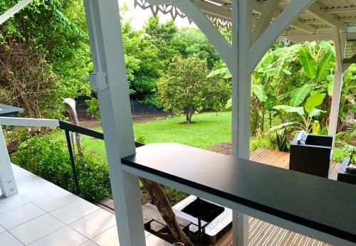 a porch with a table and a view of a garden at LODGE PAMPLEMOUSSE avec PISCINE privative , dans parc calme à 500 m plage in Le Carbet