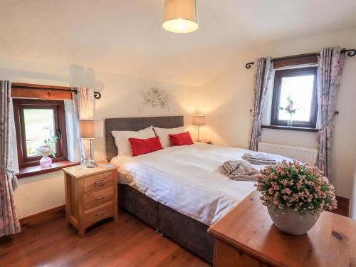 a bedroom with a large bed and two windows at Bobbin Cottage in Staveley