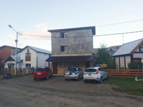 tres autos estacionados en un estacionamiento frente a una casa en Chaltén Apart 365 en El Chaltén