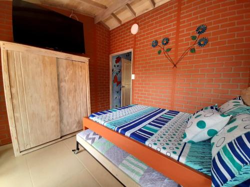 a bedroom with a bed and a brick wall at Hostal Bralgijon Capurganá in Capurganá
