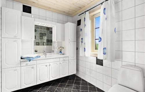 a white bathroom with a sink and a window at Awesome Home In Norheimsund With 5 Bedrooms, Sauna And Wifi in Norheimsund