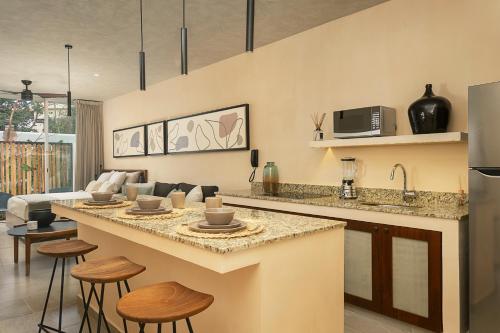 a kitchen and living room with a counter and stools at Modern Studio Pool Access Near Downtown A105 in Tulum