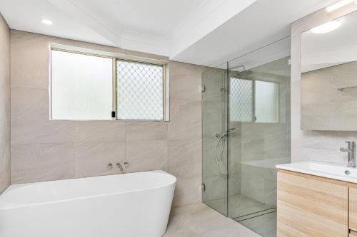 a bathroom with a tub and a glass shower at 4/84 Lawson Street - Beach Haven 4 in Byron Bay
