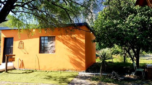 a small yellow and orange house with a tree at Casa "Hielo" Potrero Chico in Hidalgo