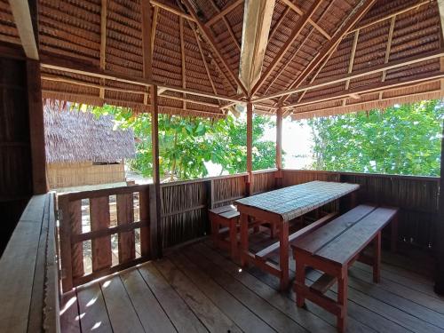 a wooden porch with a table and bench on it at Warahnus dive homestay in Kri