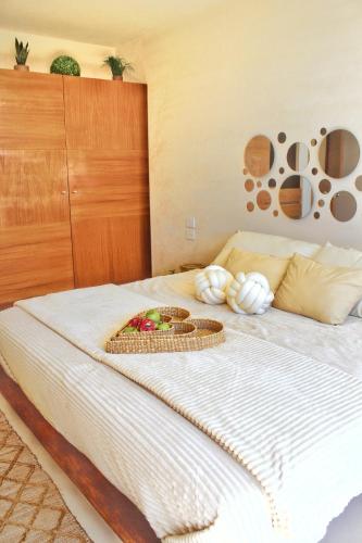 a bed with a bowl of fruit and baskets on it at Heart & Soul PH Suite Tulum in Tulum