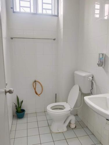 a white bathroom with a toilet and a sink at D'Irish Homestay Wakaf Che Yeh in Kota Bharu