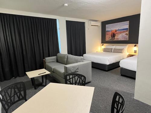 Habitación de hotel con 2 camas y sofá en Nightcap at Barkly Hotel, en Mount Isa