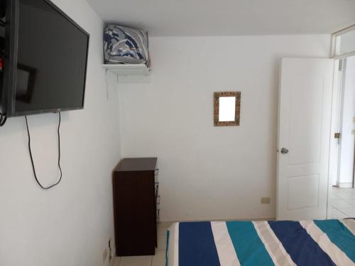 Schlafzimmer mit einem Flachbild-TV und einem Bett in der Unterkunft Minidepartamento en San Bartolo - VISTA AL MAR in San Bartolo