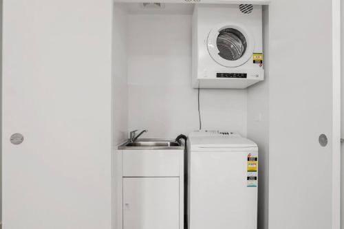 uma pequena cozinha com um micro-ondas por cima de um frigorífico em Beautiful one bedroom apartment in St Leonards-ATC62209 em Sydney