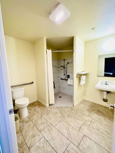 a bathroom with a toilet and a shower and a sink at King's Inn Motel in Kingsburg