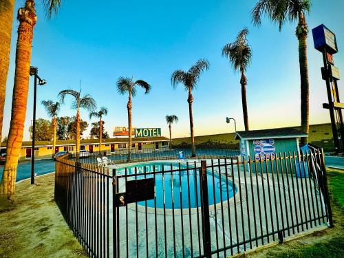 a pool with palm trees in front of a resort at King's Inn Motel in Kingsburg