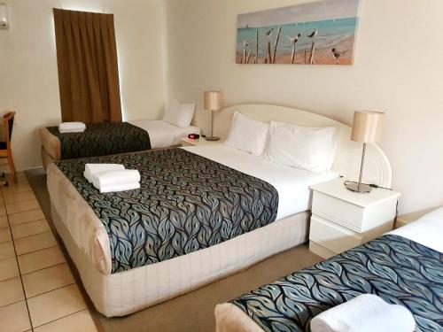 a hotel room with two beds and a table at Rockhampton Palms Motor Inn in Rockhampton