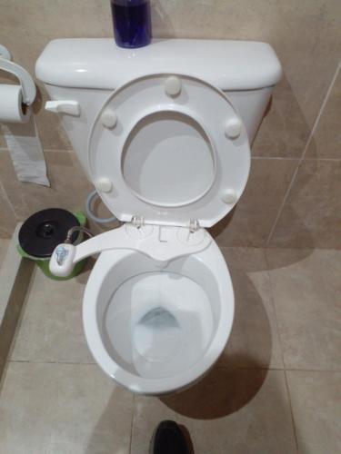 a white toilet with the seat up in a bathroom at Ventania in Tornquist