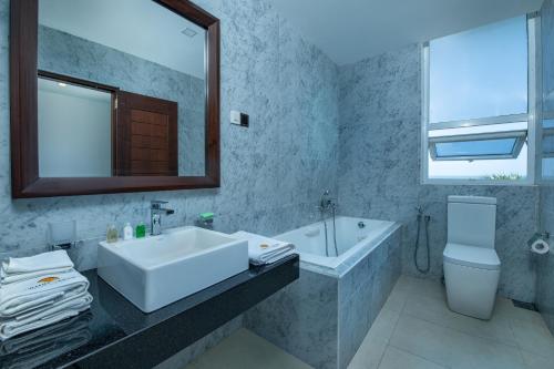 a bathroom with a sink and a tub and a mirror at Grand Samudra Hotel in Tangalle