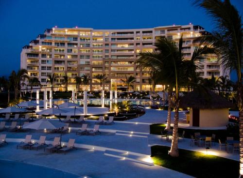 un gran edificio con mesas, sillas y palmeras en Beachfront Condo DelCanto Resort, en Nuevo Vallarta 