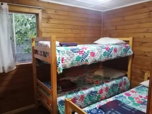 a room with two bunk beds and a window at Agradable Cabaña con Gran Piscina y Tinaja in Quillón