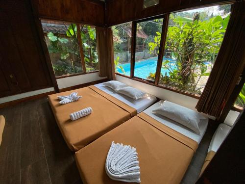 two beds in a room with a view of a pool at Taman Dolan Home & Resort in Batu