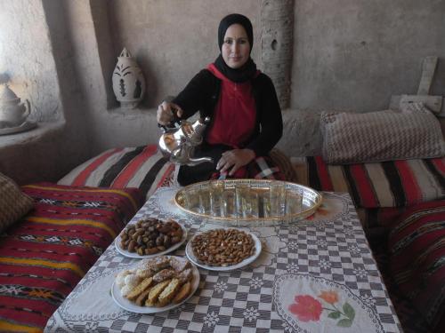 Une femme assise à côté d'une table avec de la nourriture dans l'établissement Auberge Migusta, à Skoura