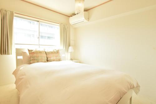 una camera bianca con un grande letto e una finestra di Nippombashi kaikan 605 ad Osaka