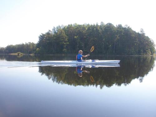 a man is rowing a boat on a lake at Hedenstugan B&B Hotel in Bergby