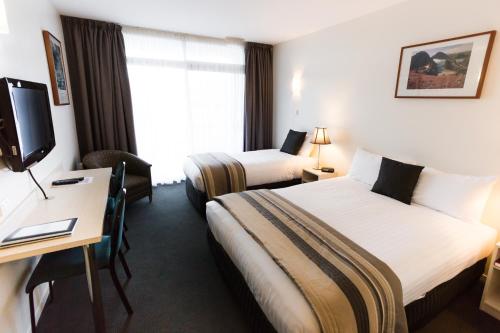 Cette chambre comprend deux lits, un bureau et une télévision. dans l'établissement Shoreline Hotel, à Hobart
