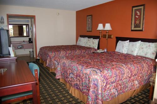a hotel room with two beds and a television at Executive Inn and Suites Springdale in Springdale