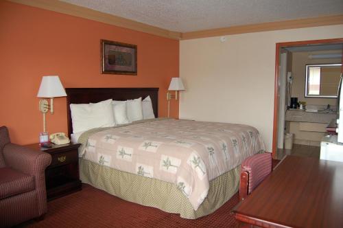 a hotel room with a bed and a table and a chair at Executive Inn and Suites Springdale in Springdale