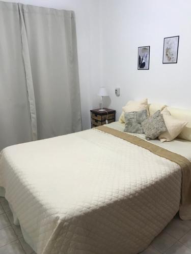 a bedroom with a large bed with white sheets at Comodo departamento centrico in San Pedro