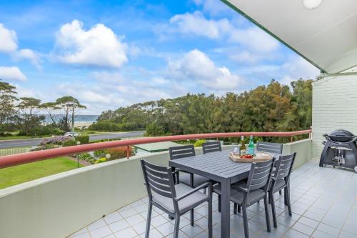 a table and chairs on a balcony with a grill at Fathoms 17 in Mollymook
