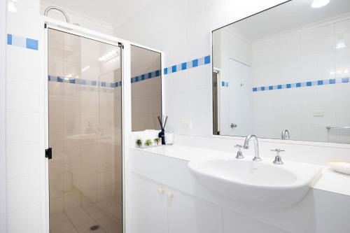 a white bathroom with a sink and a shower at Fathoms 17 in Mollymook
