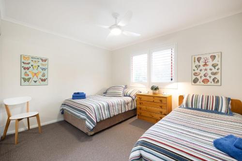 a bedroom with two beds and a dresser and a window at Fathoms 17 in Mollymook