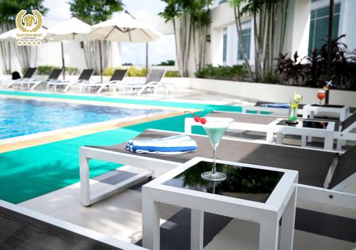 - une piscine avec un verre de martini sur une table à côté de la piscine dans l'établissement Tan Son Nhat Saigon Hotel, à Hô-Chi-Minh-Ville