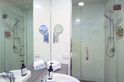 y baño con ducha, lavabo y espejo. en Absolute Lakefront Location - 3 bedroom apartment, en Queenstown