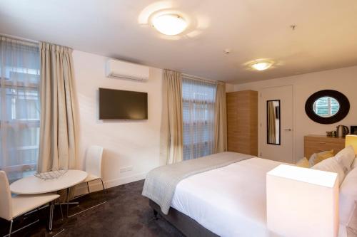 1 dormitorio con cama, mesa y TV en Absolute Lakefront Location - 3 bedroom apartment, en Queenstown
