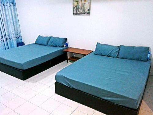 Duas camas com almofadas azuis num quarto em “Alan Homestay” Pangkor Lot 10 em Kampong Sungai Udang