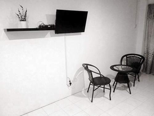 two chairs and a table with a television on a wall at “Alan Homestay” Pangkor Lot 10 in Kampong Sungai Udang