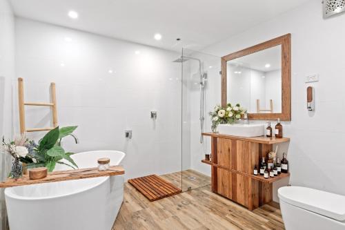 bagno con vasca, lavandino e specchio di Bondi Breeze Apartments a Sydney